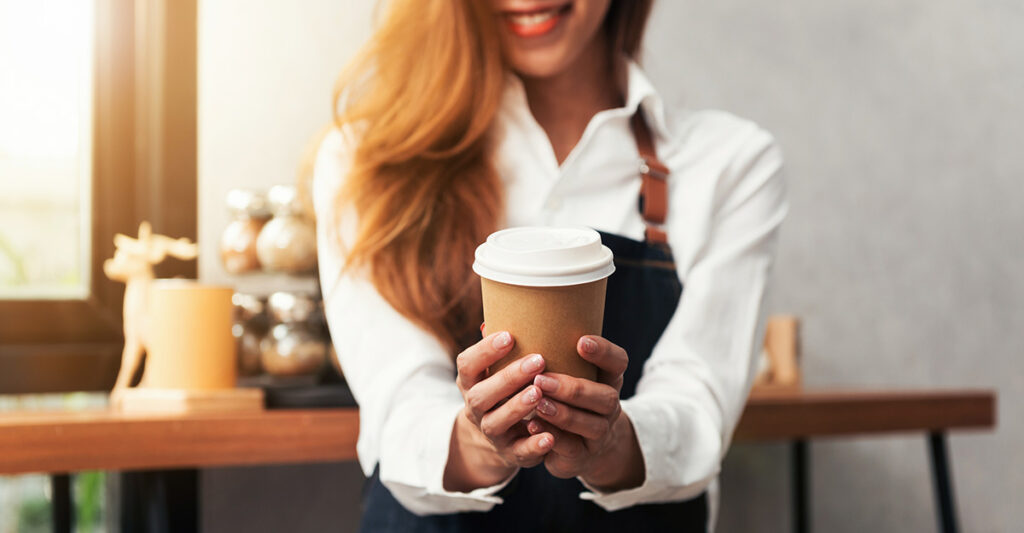 Close up of a young Asian female barista hold a cup of coffee se